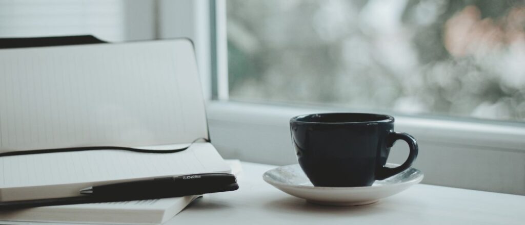 A serene scene with a coffee cup and notebook by a window, perfect for calm mornings.